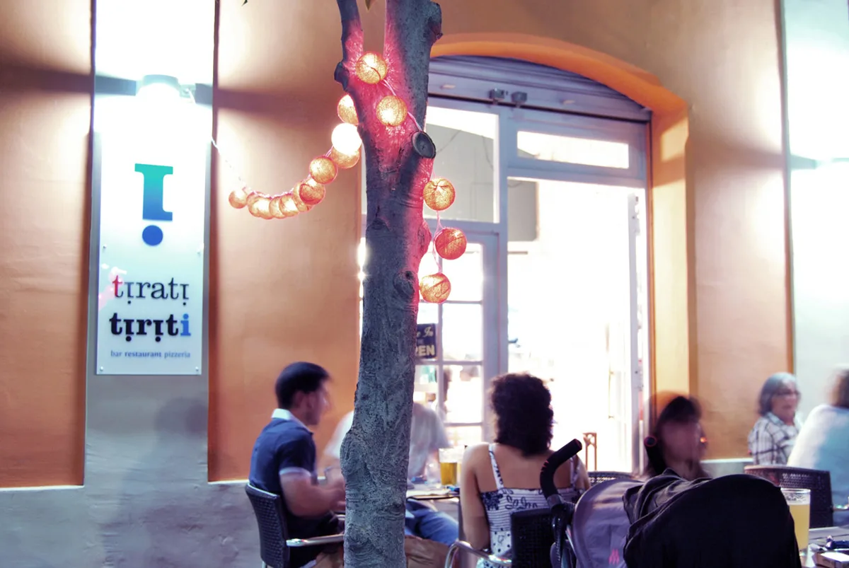 Entrada del Tiriti adornada con guirnaldas de luces y gente cenando en la terraza