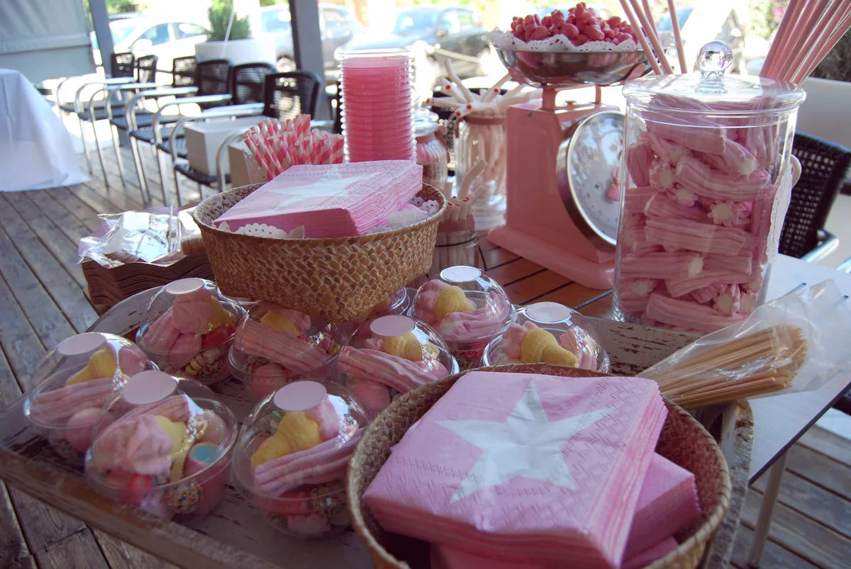 Taula de llaminadures roses amb pots de caramels per a una festa