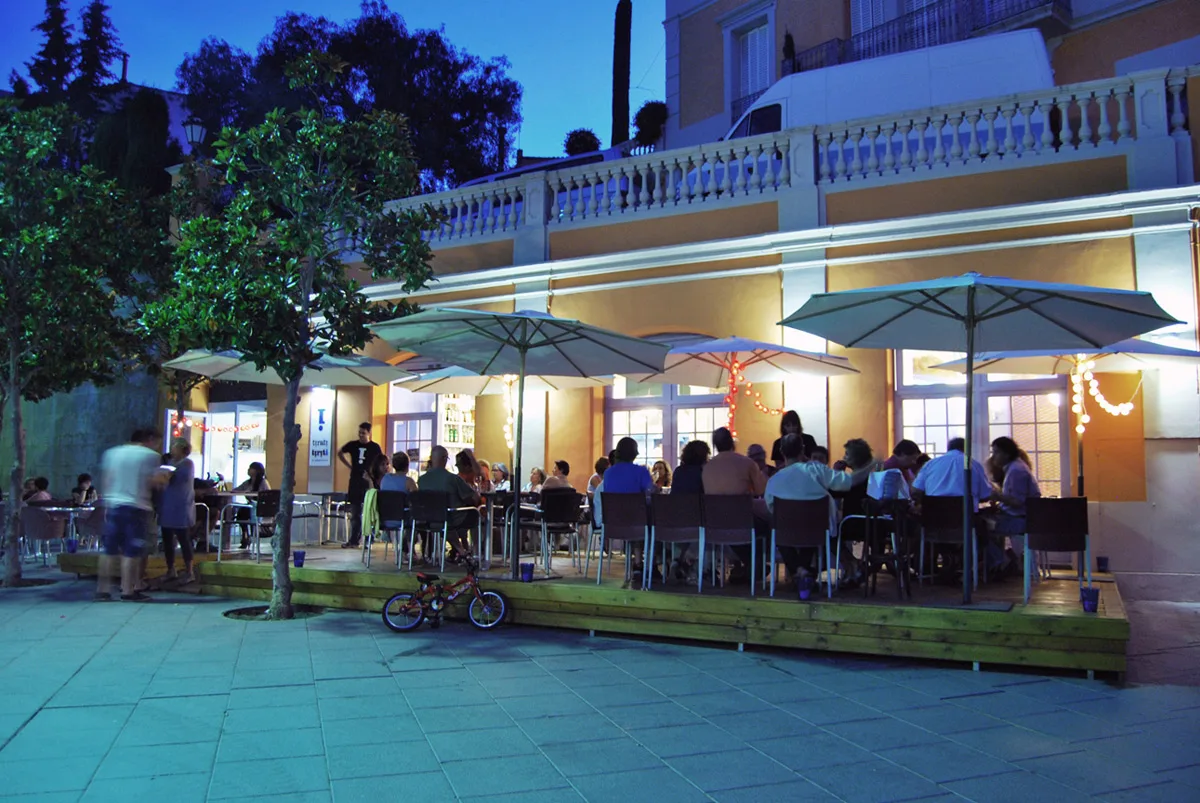 Terrassa amb para-sols davant de la façana del Tiriti, a la plaça, en fer-se fosc